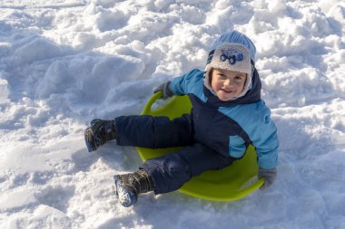 Cherkasy, Ukrayna. 01.05.2019. Kızakta oturan ve kameraya gülümseyen çocuk portresi.