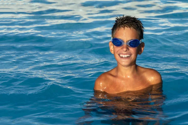 Χαρούμενο χαμογελαστό αγόρι με ποτήρια νερού στην πισίνα. — Φωτογραφία Αρχείου
