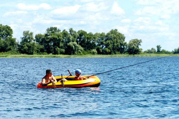 Père avec fils pêchant du bateau sur la rivière — Photo