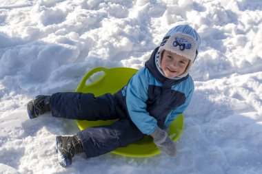 Cherkasy, Ukrayna. 01.05.2019. Kızakta oturan ve kameraya gülümseyen çocuk portresi.