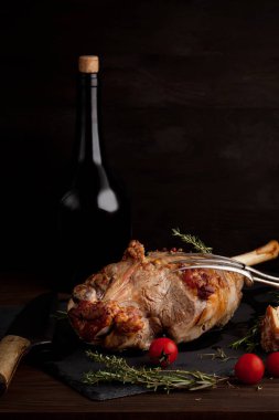 Taze kavrulmuş otlar ve şişe kırmızı şarap ile kuzu bacak