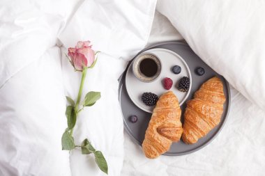 Sıcak kahve ile yatakta kahvaltı croissants