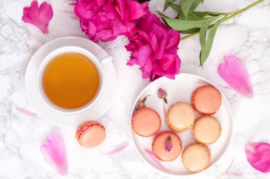 Çay saati. Düz peonies, bademli kurabiye ve çay ile ışık arka plan üzerinde yatıyordu