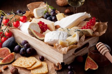 Variety of different cheese with wine, fruits and nuts. Camembert, goat cheese, roquefort, gorgonzolla, gauda, parmesan, emmental, brie clipart