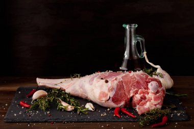Fresh raw lamb leg ready for roasting with garlic and herbs clipart