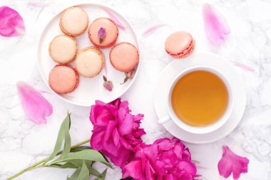 Çay saati. Düz peonies, bademli kurabiye ve çay ile ışık arka plan üzerinde yatıyordu