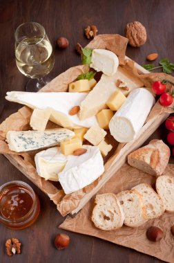 Variety of different cheese with wine, fruits and nuts. Camembert, goat cheese, roquefort, gorgonzolla, gauda, parmesan, emmental clipart