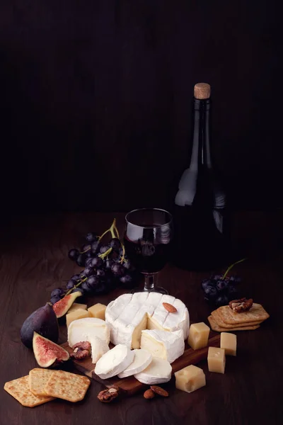 Variety of different cheese with wine, fruits and nuts. Camembert, goat cheese,  gauda,  emmental