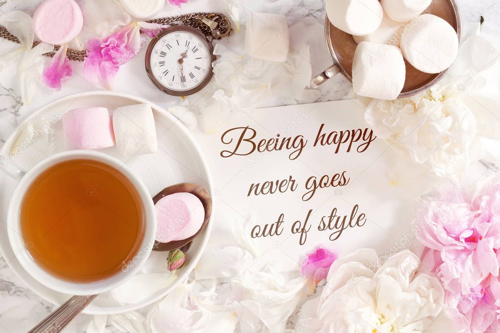 Beautiful still life with tea cup and peonies with motivation text Beeing happy never goes out of style.Top view