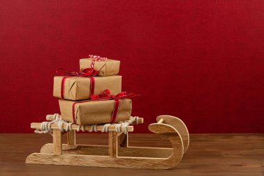 Tahta kızaklı Noel süsü, çam ağacı, içinde C harfi olan hediyeler.