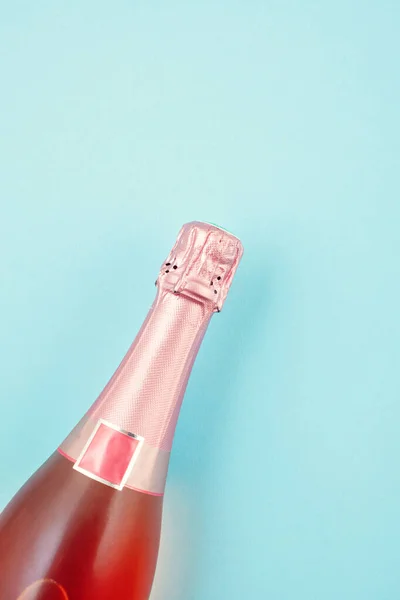 Foto creativa de la botella de champán rosa sobre fondo azul . — Foto de Stock
