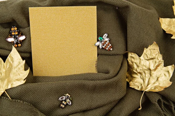 Flat lay autumn composition with blank paper sheet and a warm woolen scarf