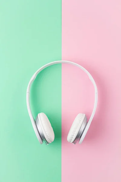 Minimale platte lay met draadloze hoofdtelefoon over roze en lichte mint achtergrond. — Stockfoto