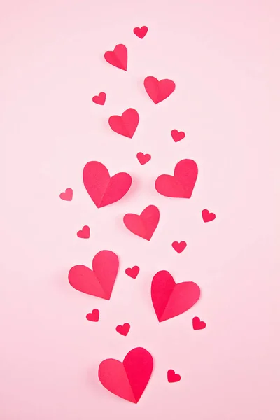 Papírové srdce přes růžové pastelové pozadí. Abstraktní pozadí s tvary střihu papíru — Stock fotografie