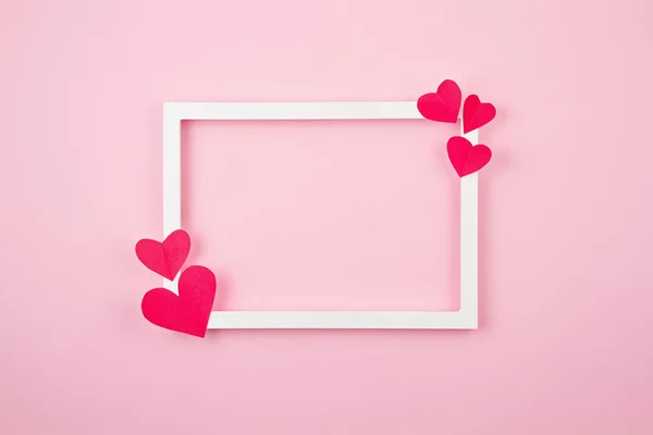 Бумажные сердца и белая рамка на розовом пастельном фоне. Love, Sainte Valentine, mother 's day, birthday cards, invitation, celebration concept — стоковое фото