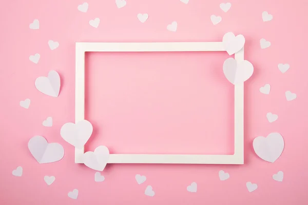 Corações de papel e moldura branca sobre o fundo pastel rosa. Amor, Sainte Valentine, dia da mãe, cartões de felicitações de aniversário, convite, conceito de celebração — Fotografia de Stock