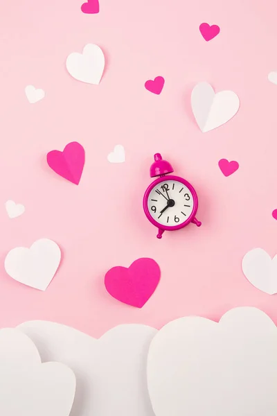 Paper hearts and alarm clock over the pink pastel background. Love, Sainte Valentine, mother's day, birthday greeting cards, invitation, celebration concept