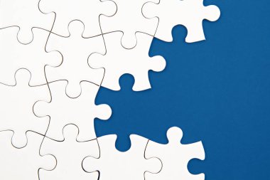 Mavi arka planda beyaz yapboz ve kayıp parçalar. Tamamlanmamış ögeler, çözüm arama kavramı