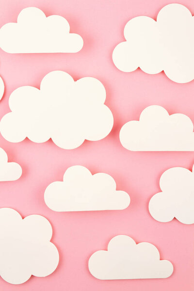 Белая бумага вырезает облака на розовом фоне
.