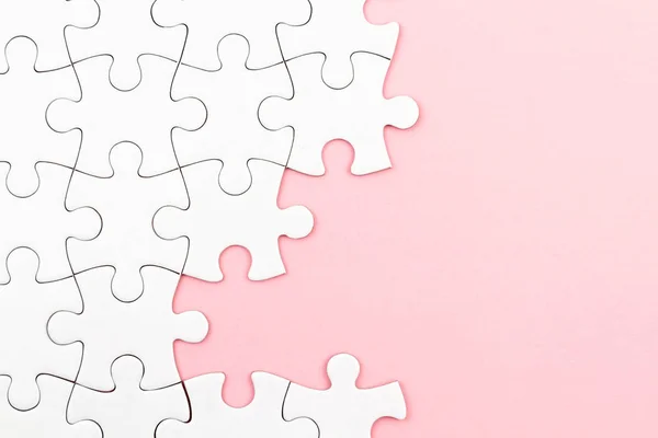 Puzzle bianco su sfondo rosa con pezzi mancanti. Elementi incompleti, concetto di ricerca di soluzioni — Foto Stock