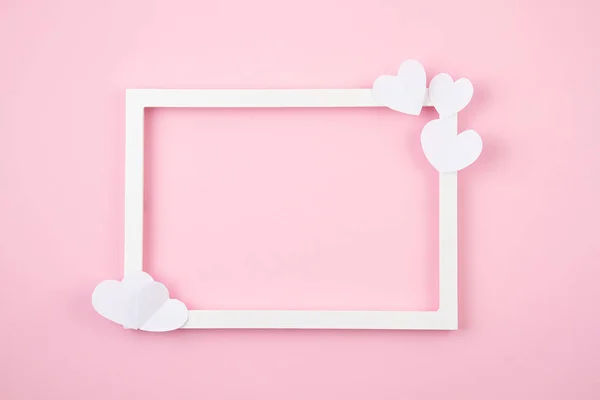 Coeurs en papier et cadre blanc sur le fond rose pastel. Amour, Sainte Valentin, Fête des mères, cartes de vœux d'anniversaire, invitation, concept de fête — Photo