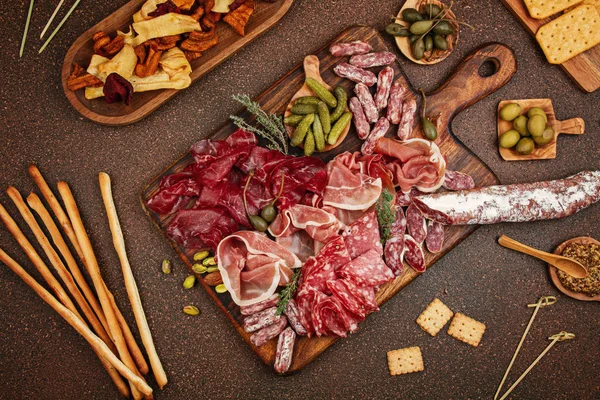 Appetizers table with differents antipasti, cheese, charcuterie, snacks and wine. Sausage, ham, tapas, olives, cheese and crackers for buffet party.