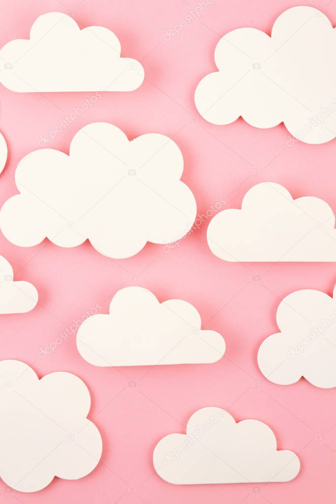 White paper cut out clouds over pink background.