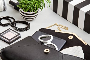Kadın moda aksesuarları, güneş gözlükleri, not defteri, makyaj malzemesi ve siyah beyaz renkli el çantası. Güzellik, kentsel kıyafet ve moda konsepti