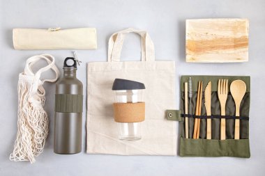 Sıfır atık. Çevre dostu bambu çatal bıçak takımı, ağ pamuk torbası, yeniden kullanılabilir kahve bardağı ve su şişesi. Sürdürülebilir, etik, plastik içermeyen fikir