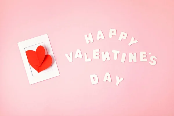 Tarjeta de felicitación con corazones de papel rojo y texto Feliz día de San Valentín sobre fondo rosa. Amor, San Valentín concepto del día — Foto de Stock