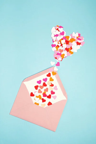 Pink envelope with heart shaped confetti over the blue background. Love, letter, message, saint valentines day concept — 스톡 사진