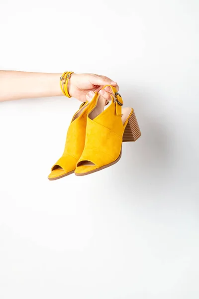 Жіноча рука тримає жовті жіночі модні аксесуари, взуття. Краса, покупки, міське вбрання та ідея модних тенденцій — стокове фото