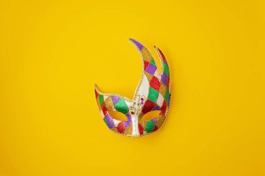 Şenlikli, renkli Mardi Gras ya da karnaval maskesi ve sarı arka planda aksesuarlar. Parti davetiyesi, tebrik kartı, Venedik karnavalı kutlama konsepti. Düz konum, üst görünüm, kopyalama alanı