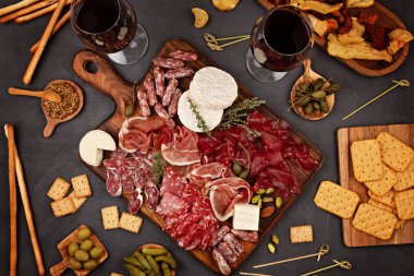 Farklı aperatifler, antipasti, şarküteri, aperatif ve şarap. Sosis, jambon, tapas, zeytin, peynir ve açık büfe partisi için kraker. Üst manzara, düz uzanma