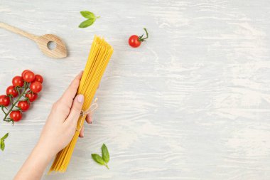 İtalyan makarnası pişirmek için spagetti ve malzeme tutan bir kadın. Spagetti, domates, yağ, sarımsak, parmezan. Geleneksel italyan kümes konseptinin en üst görüntüsü