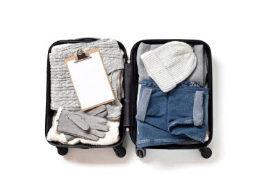 Sonbahar için günlük giysiler ve açık bavulla yatıyordu. Kış tatilleri beyaz arka plandaydı. Kış tatili, seyahat, turizm, uçuş valizi konsepti. Üst görünüm