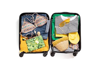 Beyaz arka planda yaz tatili için açık bavul ve günlük kıyafetlerle yatıyordu. Yaz tatili, seyahat, turizm, uçuş valizi konsepti. Üst görünüm