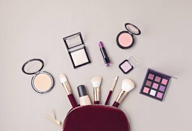 Profesyonel dekoratif kozmetik setleri, makyaj aletleri ve gri arka planda fotokopi alanı olan kadın aksesuarlarıyla yatıyordu. Güzellik blogu, moda, parti ve alışveriş konsepti. Üst görünüm