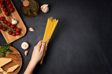 İtalyan makarnası pişirmek için spagetti ve malzeme tutan bir kadın. Spagetti, domates, yağ, sarımsak, parmezan. Geleneksel italyan kümes konseptinin en üst görüntüsü