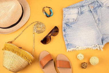 Kadın moda aksesuarları, kot şortlar, şapka, sarı arka planda güneş gözlüğü. Moda, çevrimiçi güzellik blogu, yaz tarzı, alışveriş ve trend konsepti. Üst görünüm