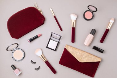 Profesyonel dekoratif kozmetik setleri, makyaj aletleri ve gri arka planda fotokopi alanı olan kadın aksesuarlarıyla yatıyordu. Güzellik blogu, moda, parti ve alışveriş konsepti. Üst görünüm