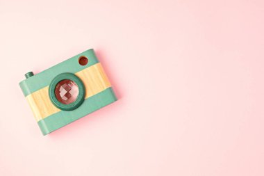 Oyuncak ahşap kamera ve pembe arka planda kalplerle yatıyordu. Sosyal medya, paylaşımlar, beğeni, takipçiler, online fotoğrafçılık dersleri konsepti. Üst görünüm, alanı kopyala.
