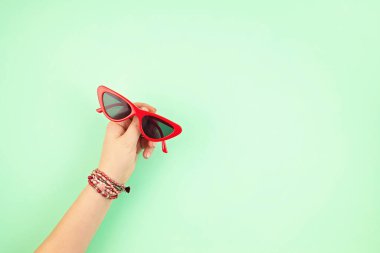 Kadın eli, şık güneş gözlüğü tutuyor. Yaz tatili, tatil, yaz tatili moda konsepti. Üst Manzara. Düz yatıyordu