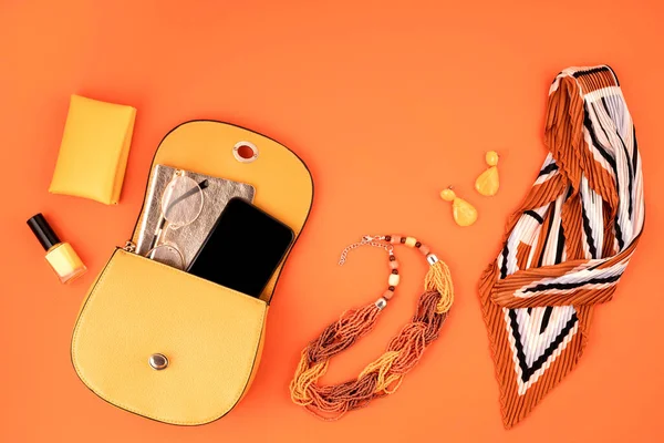 Flat lay with woman fashion accessories in yellow color over orange leather textured background. Fashion, online beauty blog, summer style, shopping and trends concept