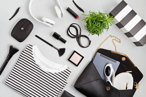 Woman fashion outfit and accessories, handbag, notepad, makeup and earphones in black and white colors. Beauty, urban outfit and fashion trends concept. Flat lay, top view