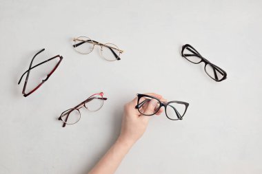 Gözlük tutan kadın. Optik mağaza, gözlük seçimi, göz testi, göz doktorunda vizyon muayenesi moda aksesuarları konsepti. Üst manzara, düz uzanma