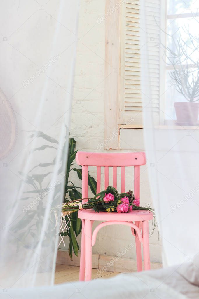 Bunch of pink roses lying on pink shabby chic style wooden chair