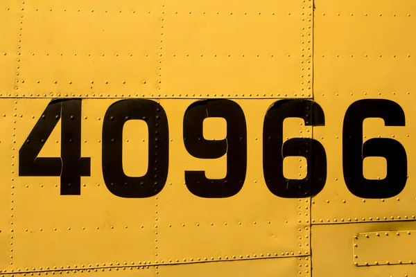 Yellow riveted metal surface with numbers — Stock Photo, Image