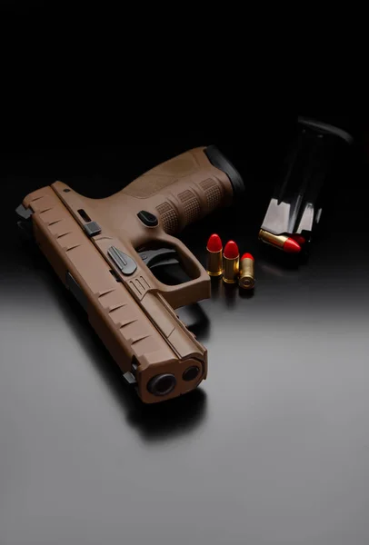 Sebuah pistol coklat modern dan amunisi di atasnya berada di punggung gelap. W — Stok Foto