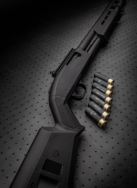 Modern zwart shotgun en munitie voor hem op een donkere achtergrond. — Stockfoto